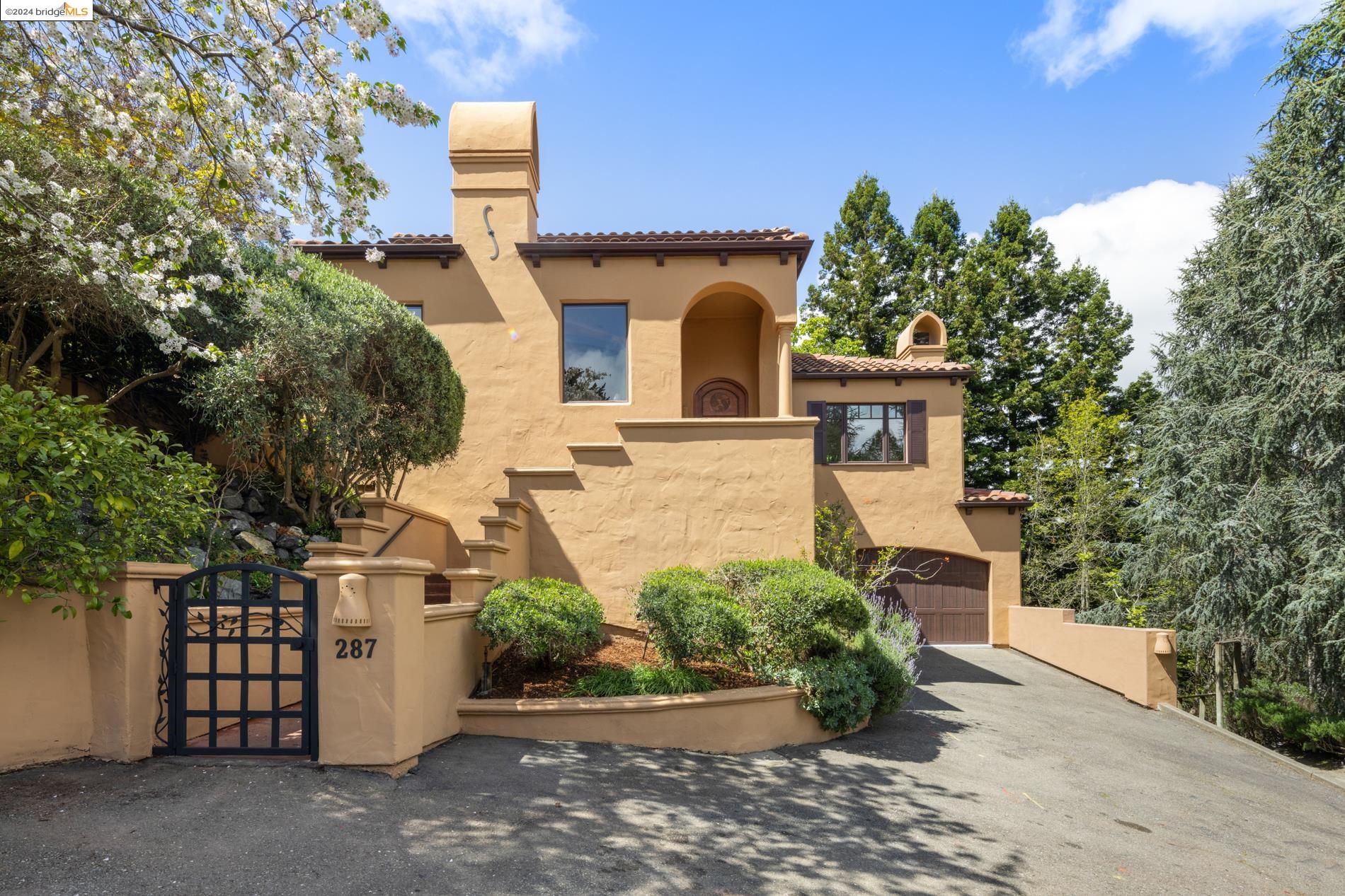 This distinctive Spanish-inspired home emanates remarkable custom craftsmanship. Its grand scale is immediately apparent upon entry, with soaring ceilings, a dramatic staircase, and clerestory windows that flood the space with natural light. The living room features a vaulted ceiling adorned with rustic wood beams and a stylish tiled fireplace. Adjacent, the kitchen boasts granite countertops and a Bay window offering tranquil garden views. On the main level are two bedrooms and a bathroom. A spacious family room offers a separate entertainment area. The upstairs primary suite includes a charming bonus room with a built-in desk and a tiled split bathroom. An additional ensuite bedroom and a laundry room complete the upper level. The expansive lot enveloped in lush landscaping provides a sense of peaceful seclusion. Separate outdoor areas provide excellent entertaining flow as well as space for relaxation and al fresco dining. Downstairs, a two-car garage and a versatile bonus room with bath offer many possibilities, whether it be a home office, gym, or creative space. Transportation options include a nearby BART station, bus lines and easy access to Hwy 13. The local Village Market, Rockridge, Piedmont Avenue and Montclair districts provide many shopping and dining options.