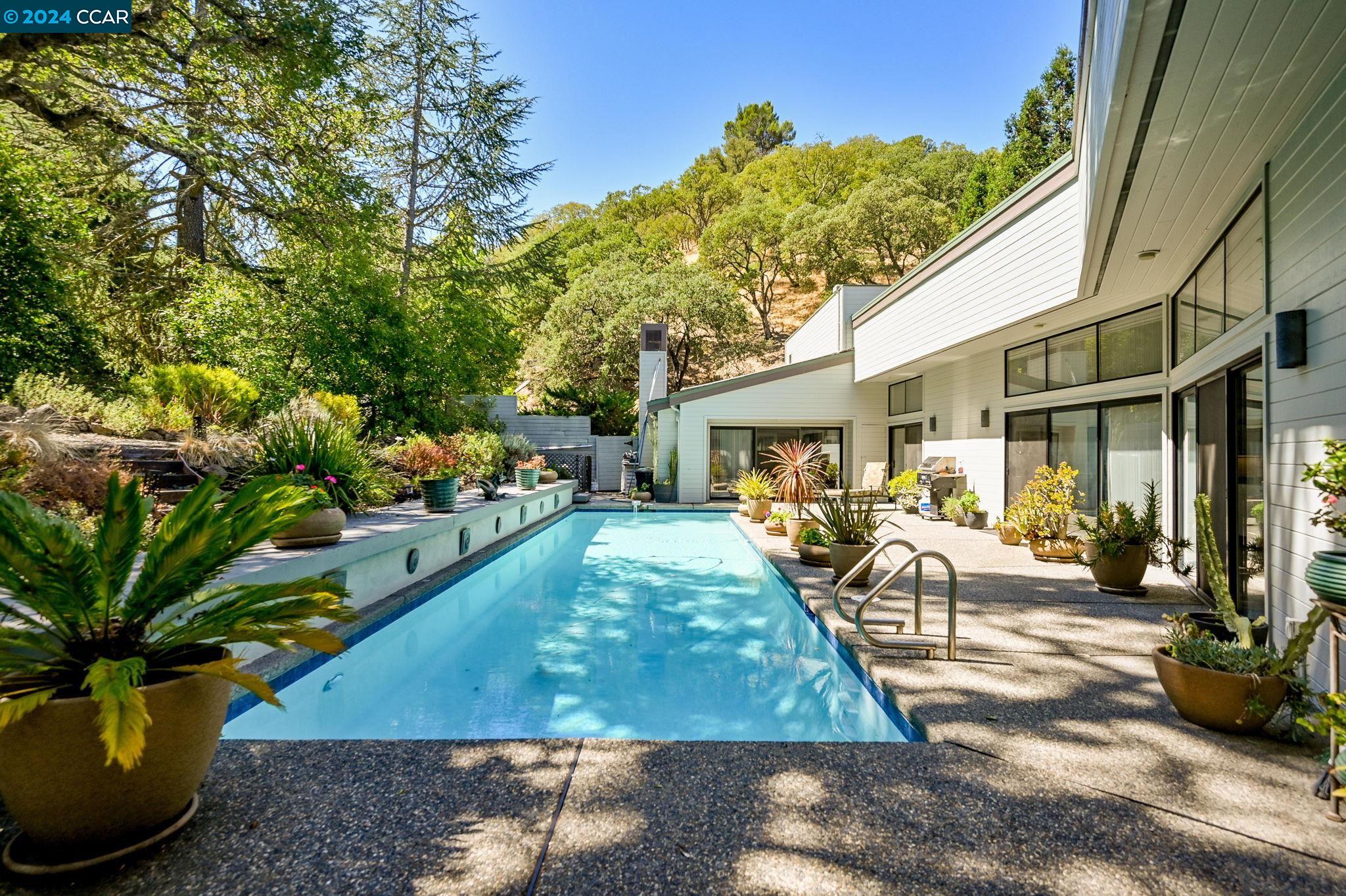Down a private country road in Tice Valley, & just 2 miles from downtown Walnut Creek, this single-level mid-century modern home offers tranquility & privacy. Situated on a .88-acre wooded lot, this sophisticated home is surrounded by oak-studded hills, providing absolute serene escape. As you approach you’re welcomed by an estate-like ambiance. The home’s approximately 3,145 sq. ft. 3 bedrooms 3 baths layout features soaring ceilings, walls of glass & picturesque views of the inviting pool & lush surroundings. Outside discover a private oasis designed for relaxation & entertainment. The expansive outdoor area boasts a sparkling pool, perfect for enjoying summer nights & hosting gatherings with friends & family. The tranquil setting is complemented by a seasonal creek and majestic oak trees. Inside, the home’s design is both elegant & functional. The open-concept kitchen features a large island & casual dining area that seamlessly flows into the great room, with stunning views of the pool. A formal dining room offers a more intimate setting for special occasions. The spacious bedrooms & artistically designed baths plus an attached 3-car garage, 2-zone HVAC, & solar.