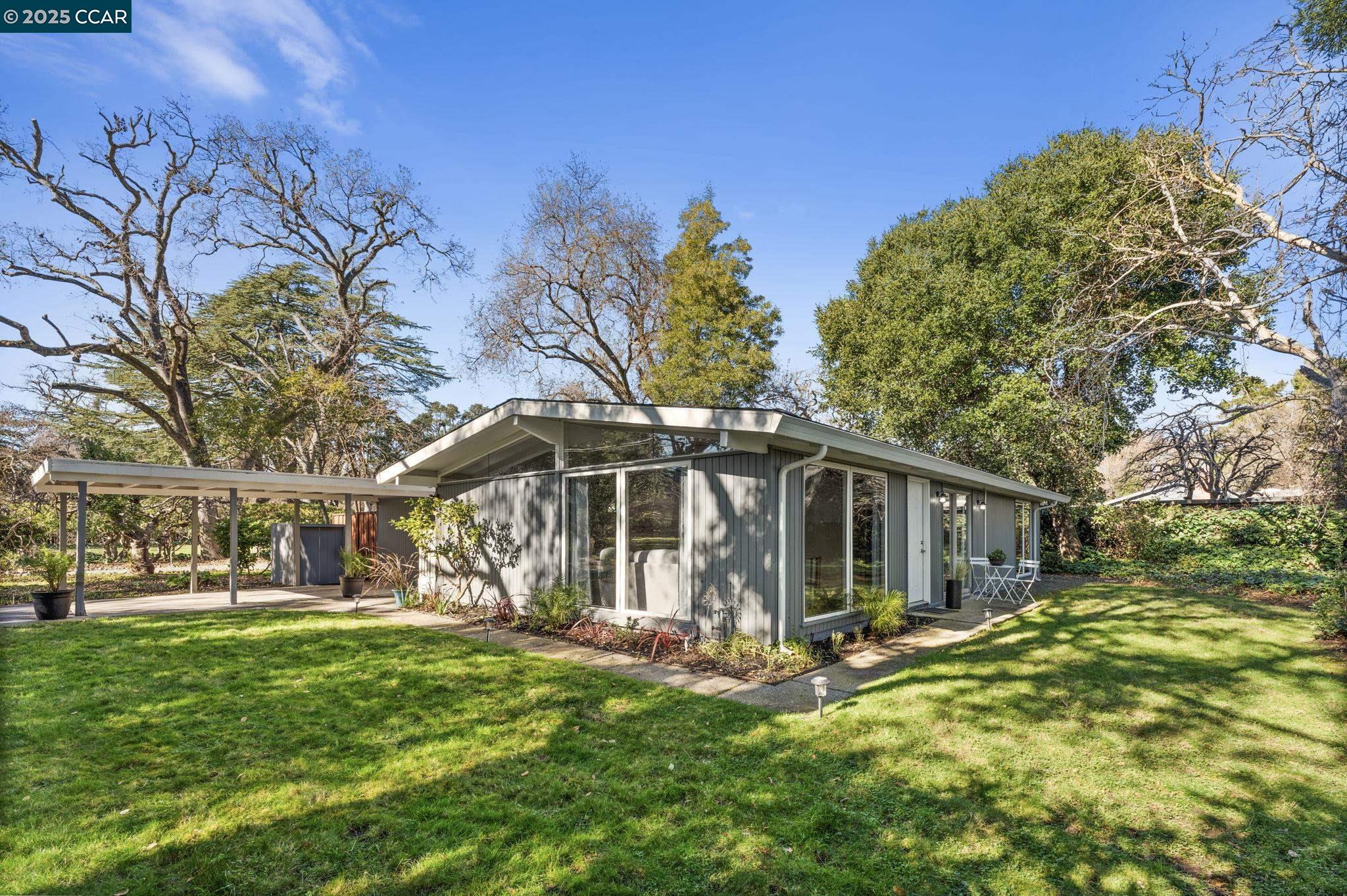 Nestled down a tranquil wooded and private lane, this updated home is brimming with mid-century modern style and sophistication and is primed for expansion! Bathed in natural light, the living room boasts a cozy wood burning fireplace with a raised hearth, laminate flooring, new light fixtures, and walls of windows looking out to the lush garden setting. A recently updated kitchen offers stylish shaker cabinetry, slab stone counters, stainless steel appliances and new designer lighting. Both bedrooms boast vaulted ceilings, transom windows, ceiling fans, and ample closet space. The updated bathroom offers a new vanity, shower over tub and new hardware and fixtures. Other features include a newer mini-split heating & air conditioning system, two sun tubes for added natural light and dual pane windows. A detached bonus room (approx. 100 sf) doubles as a laundry room, and an office, craft or storage room. Sunny, expansive, level yards boast lush lawns, a brick paver patio, towering mature trees, peaceful quietude and plenty of space for a kids play area, future home expansion and limitless backyard improvements. This sought after location is just steps to the Dewing Park Pool and is also near scenic trails and open space, easy commuting access, and 12 years of Walnut Creek Schools!