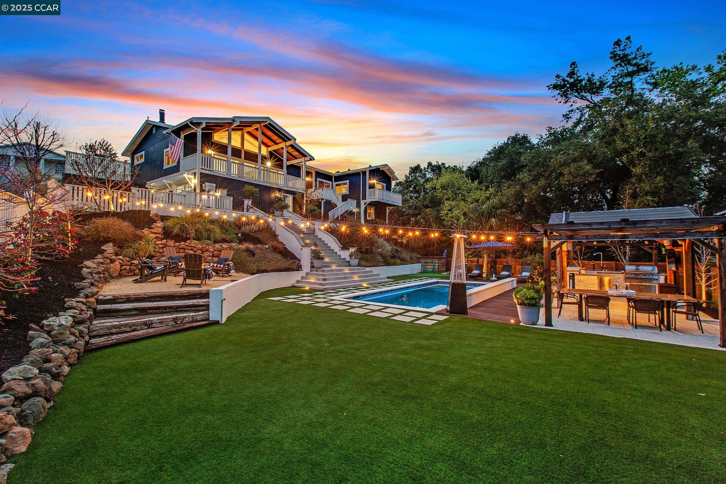 Nestled in the heart of Alamo, 100 Valley Oaks Drive is a stunningly remodeled 5-bedroom, 3.5-bathroom home offering 2,686 sq. ft. of luxurious living on a sprawling .6-acre lot. Designer touches grace every corner, from the soaring wood-paneled ceilings and cozy fireplace in the living room to the custom built-ins and dazzling chandelier in the family room. The dream kitchen boasts two-tone cabinetry, a waterfall island with breakfast bar seating, white shaker cabinets, a 6-burner gas range, stainless steel appliances, and designer pendant lighting. The oversized primary suite features its own fireplace, a private balcony, and a spa-like ensuite with a dual vanity, shower stall, and massive walk-in closet. Hardwood floors, wainscoting, recessed lighting, and elegant baseboards enhance the home’s modern charm. The backyard is a true private oasis, featuring an expansive deck, lush lawn, and sparkling pool with cascading waterfalls. A relaxing hot tub, outdoor kitchen under a charming pergola, and a professional-grade putting green create an entertainer’s dream. A batting cage adds even more versatility to this resort-like retreat. Located near top-rated schools and Roundhill Country Club, this home offers an unparalleled blend of luxury, serenity, and convenience.