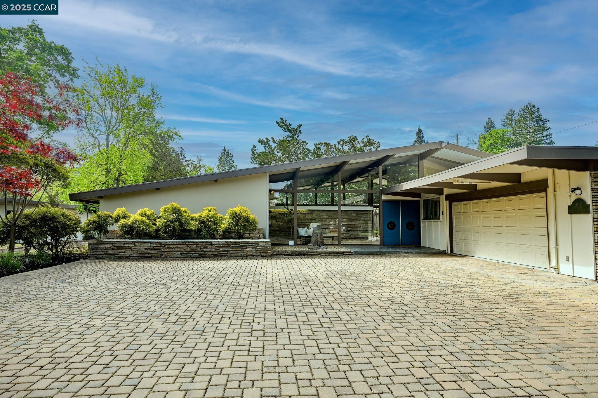 Timeless Mid-Century Modern Charm. Step into this distinctive mid-century modern home through impressive vintage double doors, where a striking foyer with black slate floors and a beautiful stone accent wall welcomes you. The expansive living and dining areas feature a magnificent wall-to-wall fireplace, creating the perfect backdrop for entertaining and celebrations throughout the year. Recently refreshed with new paint, carpet, and LTV flooring in the kitchen. Discover hidden treasures with original hardwood floors beneath most carpeted areas. The classic kitchen offers practical counter seating and abundant cabinet and counter space for the discerning home chef. With four generous bedrooms and three full bathrooms, this home provides ample space for family and guests. The bonus family room creates a versatile retreat—perfect for movie nights, game days, or quiet relaxation. Outside, mature redwoods and established trees create a serene backdrop around the property. The spacious detached shed offers endless possibilities as storage, a workshop, or creative studio. Ideally located near parks, freeway access, and top-rated schools—just a quarter mile from Las Lomas High School—this captivating property combines location with character. This unique gem won't last!