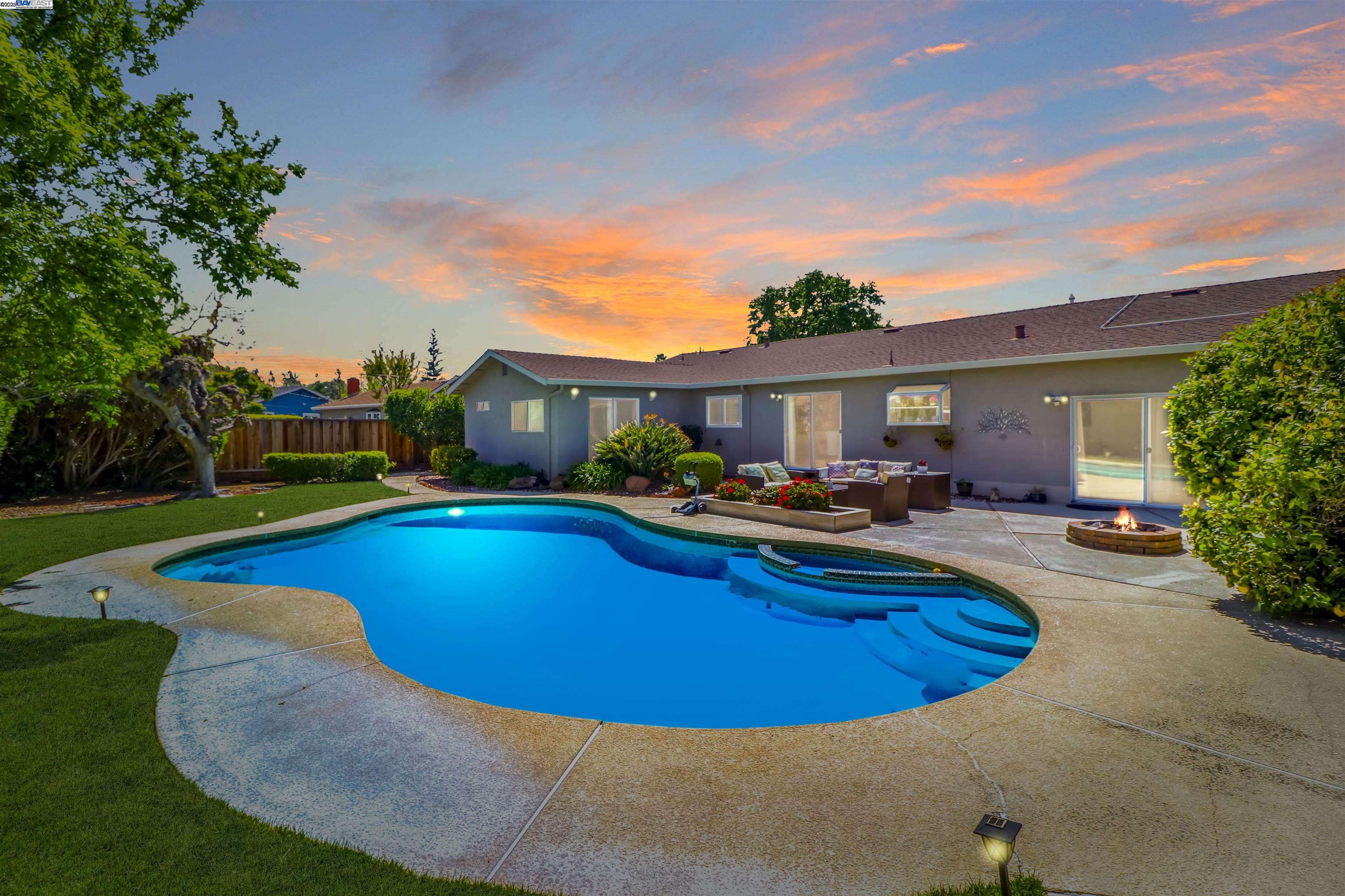 Embrace the quintessential California lifestyle in this spacious and inviting home nestled in a highly sought-after location. With its open-concept floor plan, this charming 2161 sq. ft. single-story residence exudes warmth and comfort. Step through the beautiful glass and steel front door into a welcoming entry. The kitchen has undergone a complete remodel, and cleverly connects the dining and living areas, fostering a sense of connection, making it the perfect home for entertaining and creating lasting memories with your loved ones. This magnificent home offers a perfect blend of functionality and style. The four bedrooms and two baths floor plan offers ample space for your family and guests. The primary bedroom suite boasts a sliding glass door that opens to the picturesque backyard, offering a private retreat. Perfect for entertaining guests or simply relaxing after a long day, the private marvelous backyard is generous in size and features a custom pool and spa, fire pit, ample yard space, and mature fruit trees. You can step outside from the family room, primary room, living room or second bathroom into this private oasis.  The home is equipped with solar panels, and private well for irrigation making it an efficient and environmentally friendly choice.