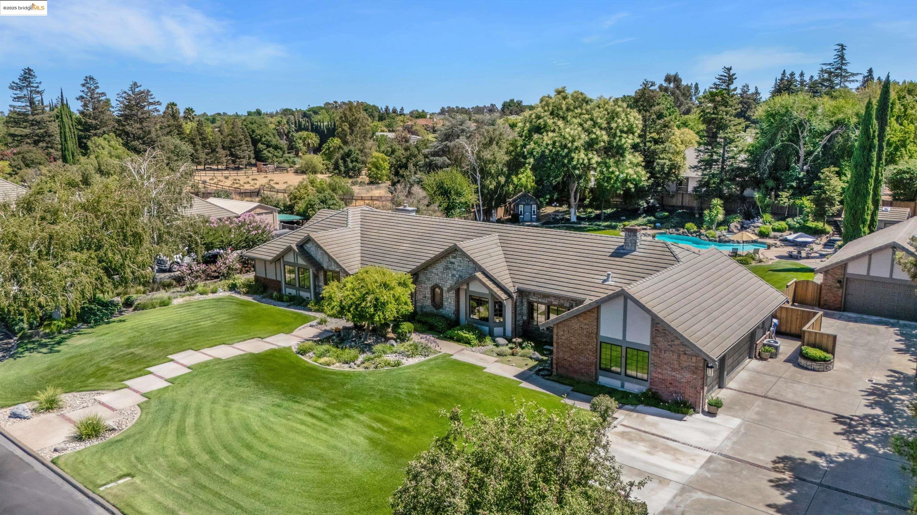 Prestigious Neroly Estates – First Time Ever on the Market. This Sbranti custom home has been cherished by the same family who designed and built it from the ground up. Set on just under an acre in coveted Neroly Estates, it commands the entire frontage of its street—a presence you can’t recreate. Inside, vaulted ceilings soar above rich custom woodwork, intricate stained-glass, marble-accented entry, hardwood floors, and timeless architectural detail. 4 bedrooms plus an executive office and dedicated storage room offer versatility. The chef’s kitchen features a Viking 6-burner range with griddle, dual ovens, granite counters, and 54 custom alder cabinets. The primary retreat boasts a pine wood ceiling, gorgeous gas fireplace, and spa-inspired bath with Swedish air tub. Outdoors, lush landscaping surrounds a resort-style pool and spa with cascading waterfall, covered patio with fireplace, and a custom playhouse with electricity. A 3-car attached garage plus detached garage offer parking or potential ADU, pool house, or workshop. 47 owned solar panels, private well, and updated exterior complete this rare opportunity.